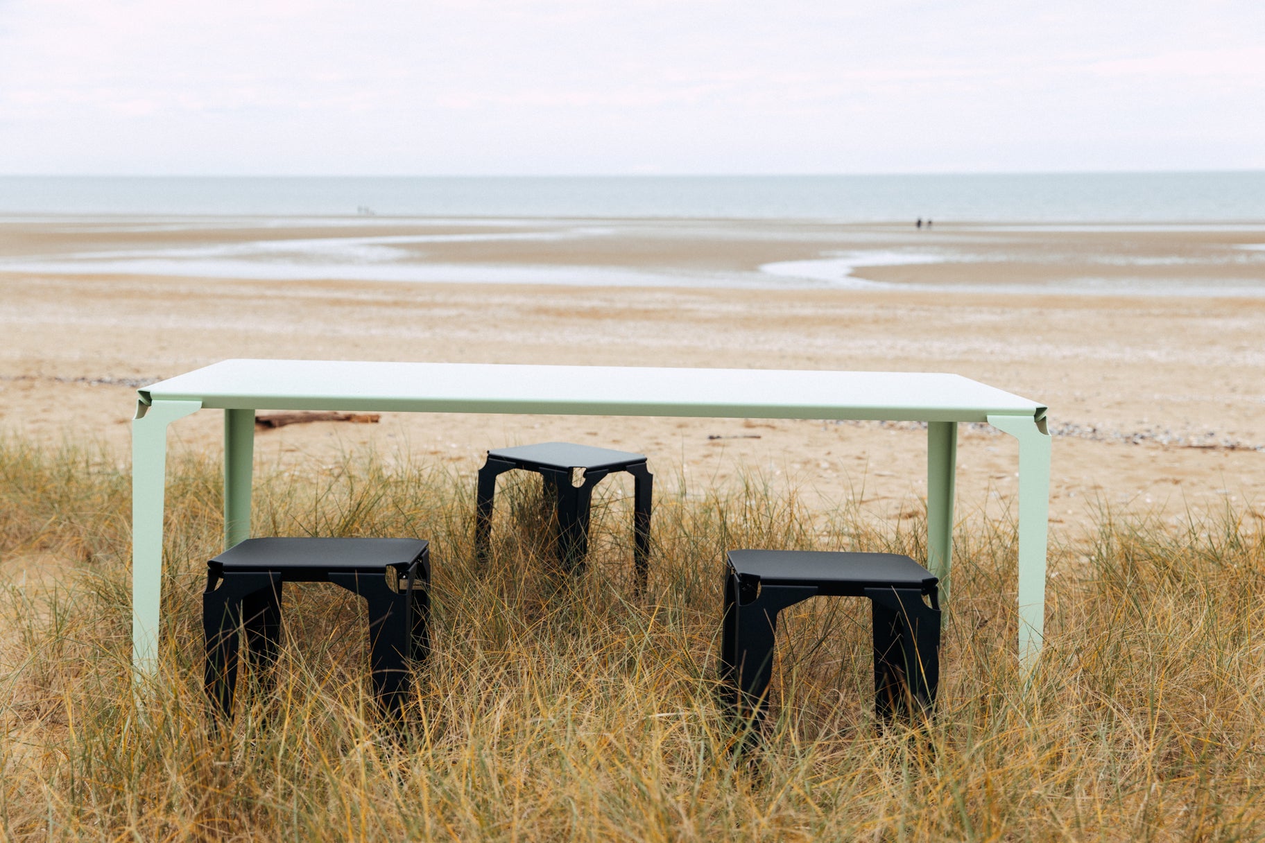 Tabourets Pontivy acier de couleur noir autour d'une table au milieu des dunes