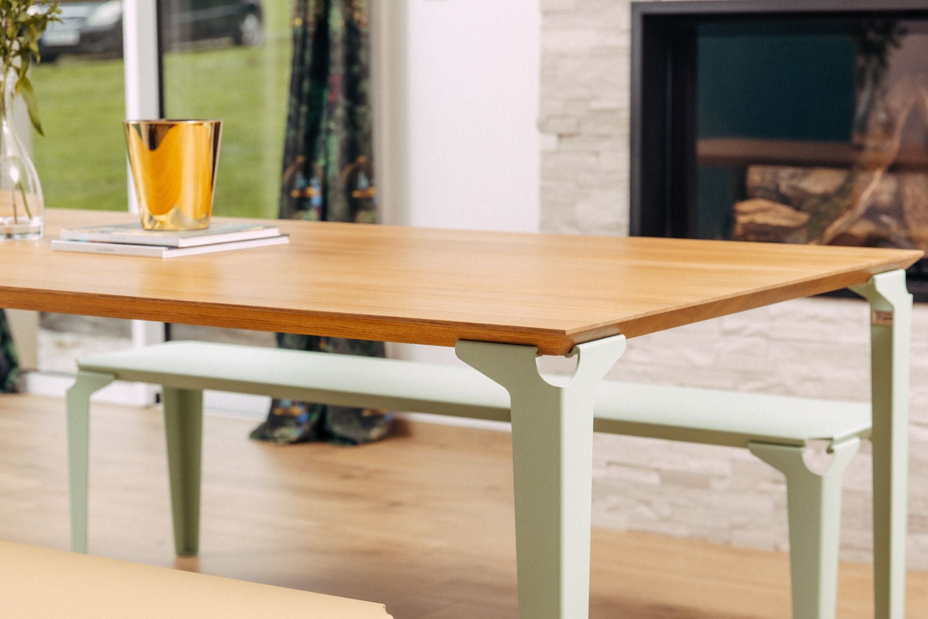 table à manger Deauville en bois massif et acier vert pastel devant une cheminée