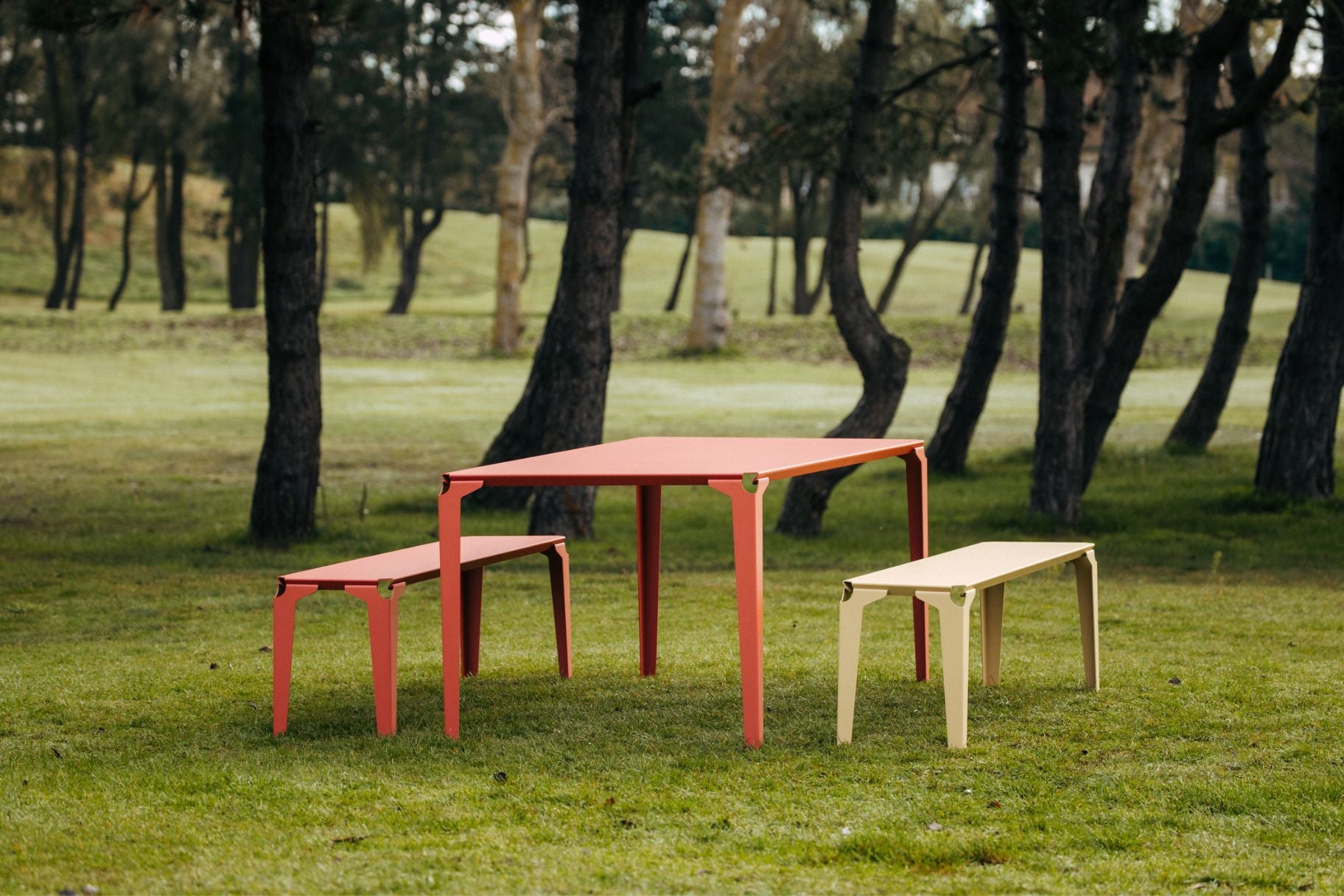 table Nantes en acier thermolaqué rose accompagné de deux banc beige et rose sous les pins