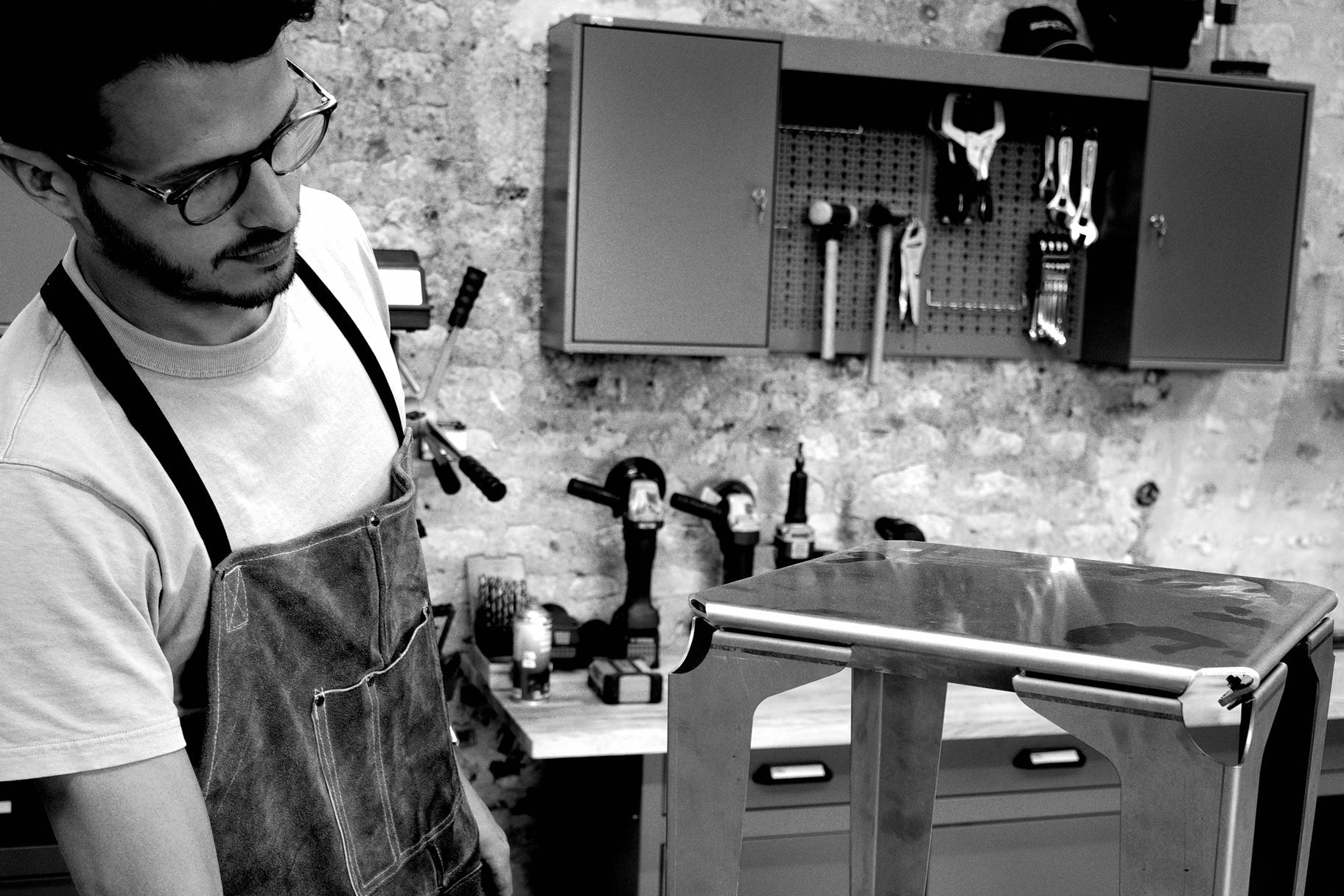 Arnold qui apprécie les finitions d'un tabouret en sortie d'atelier