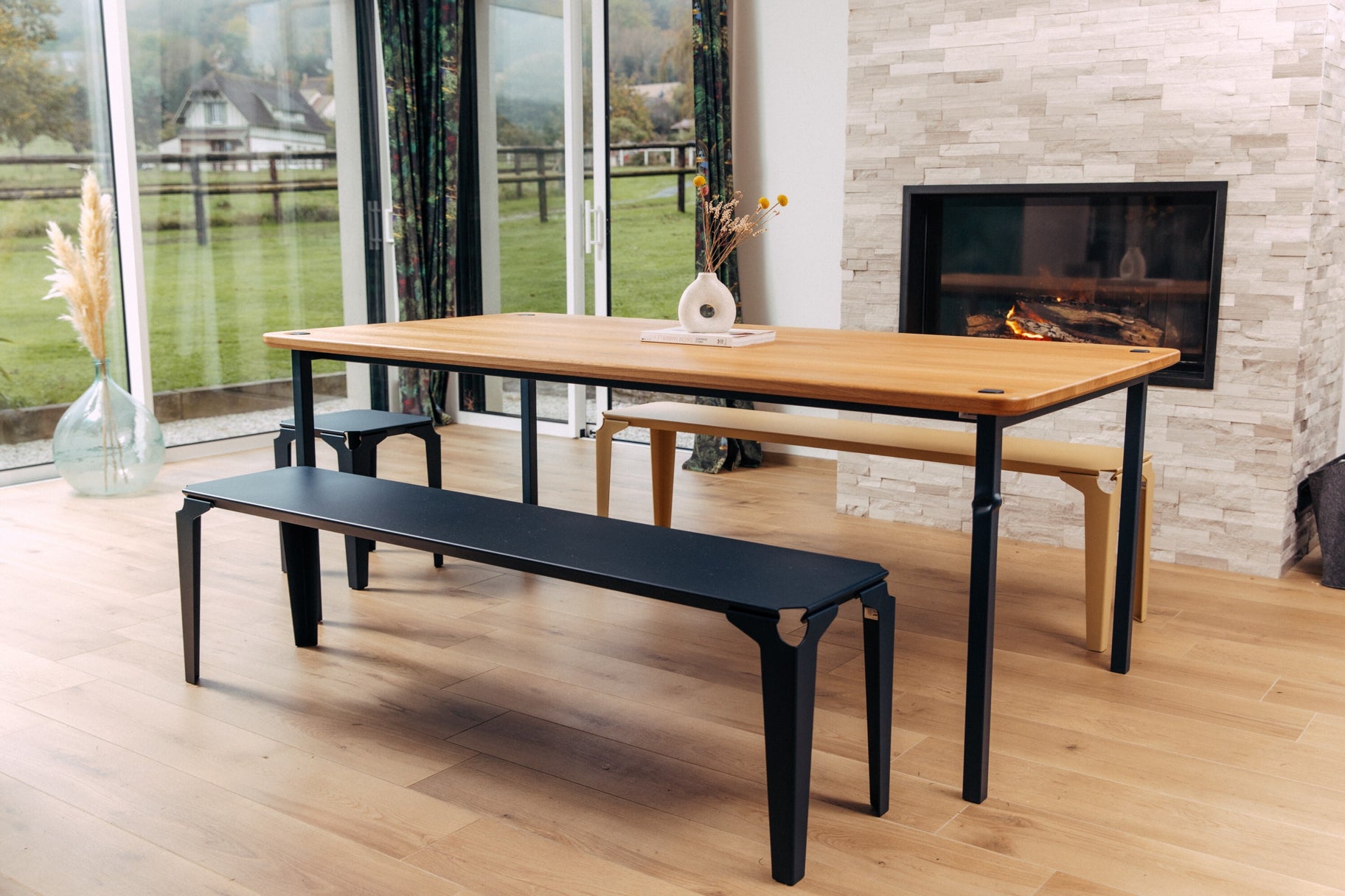 Table à manger, bancs et tabouret devant la cheminée