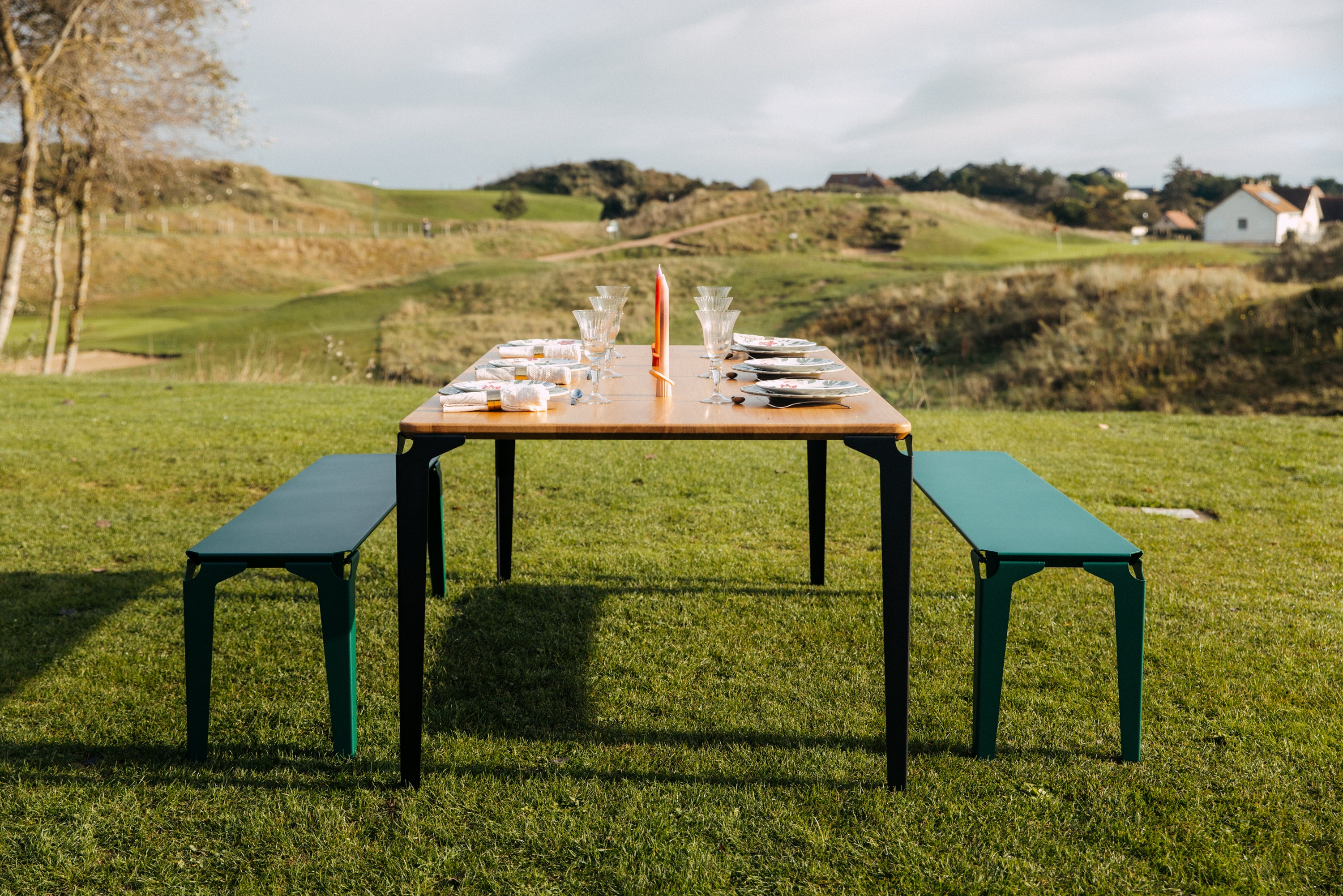 Table à manger bois et acier avec ses deux bancs dressée au milieu du golf